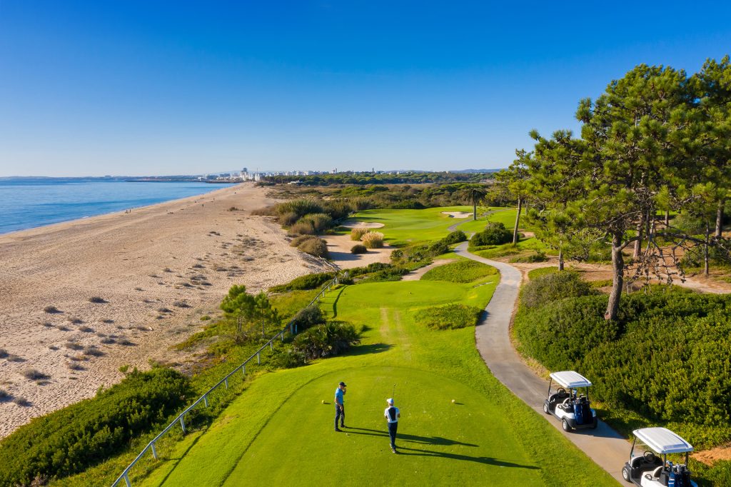Golfers enjoying a game on a green fairway near the beach, with ocean views at Vale do Lobo Resort.